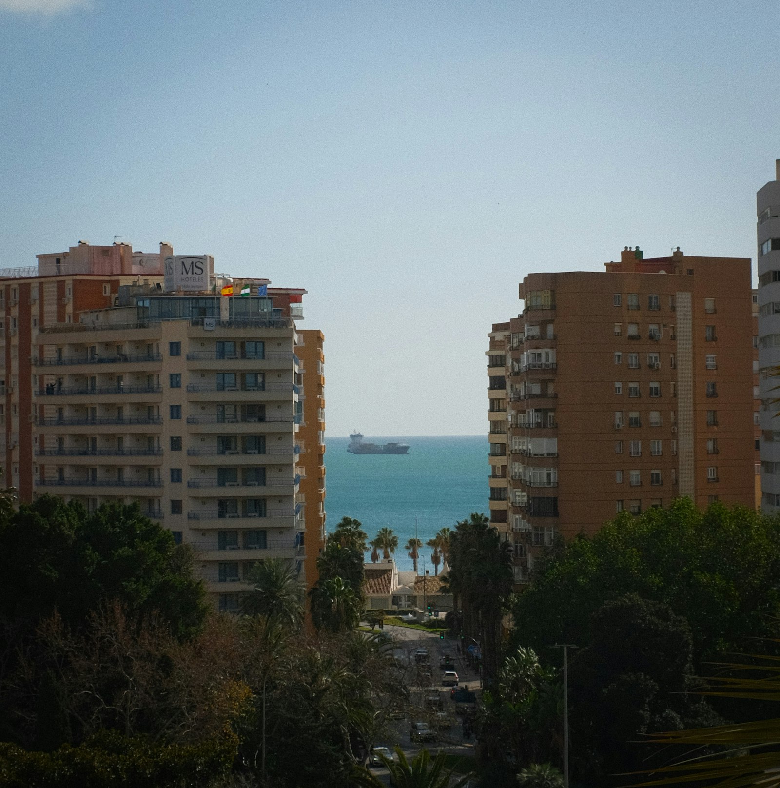 Apartamentos con vistas al mar y barco a lo lejos en la Costa Brava